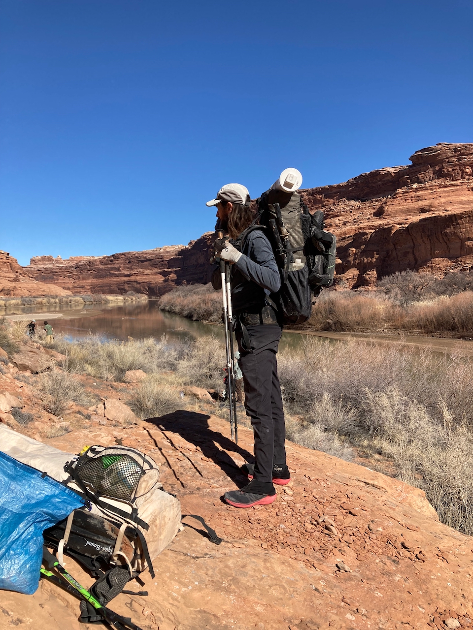 A man stands on a riverbank with the Waymark Gear Company Lite 50L on his shoulders.