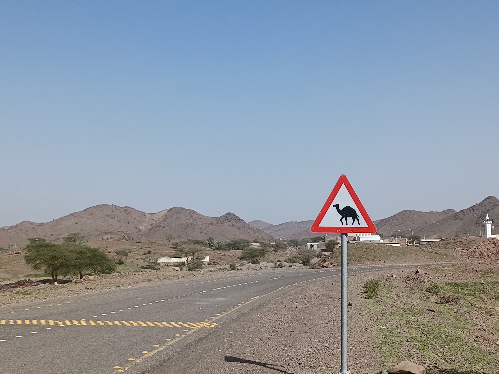 a sign on the side of a road with mountains in the background