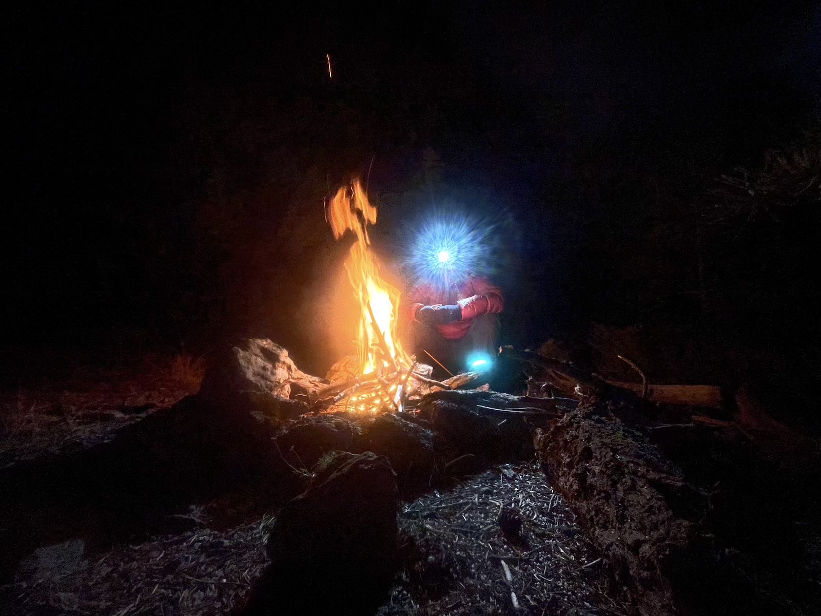 a man standing next to a fire in the dark