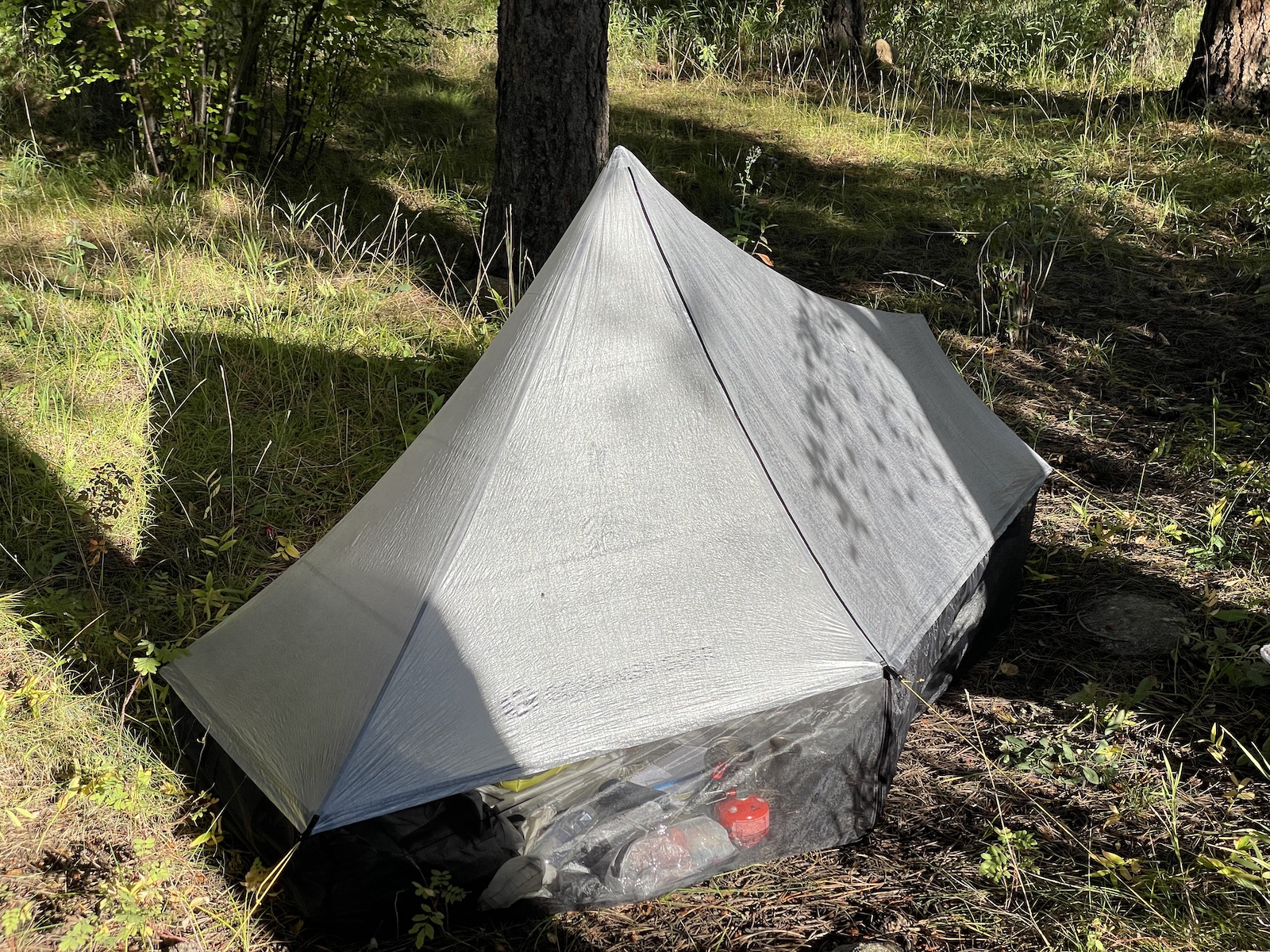 a tent in the woods with a tarp over it