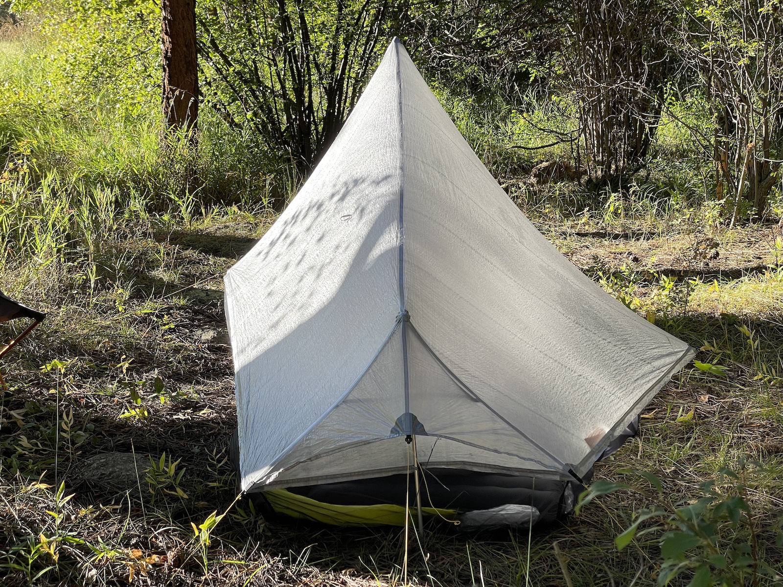 a white tent sitting in the middle of a forest