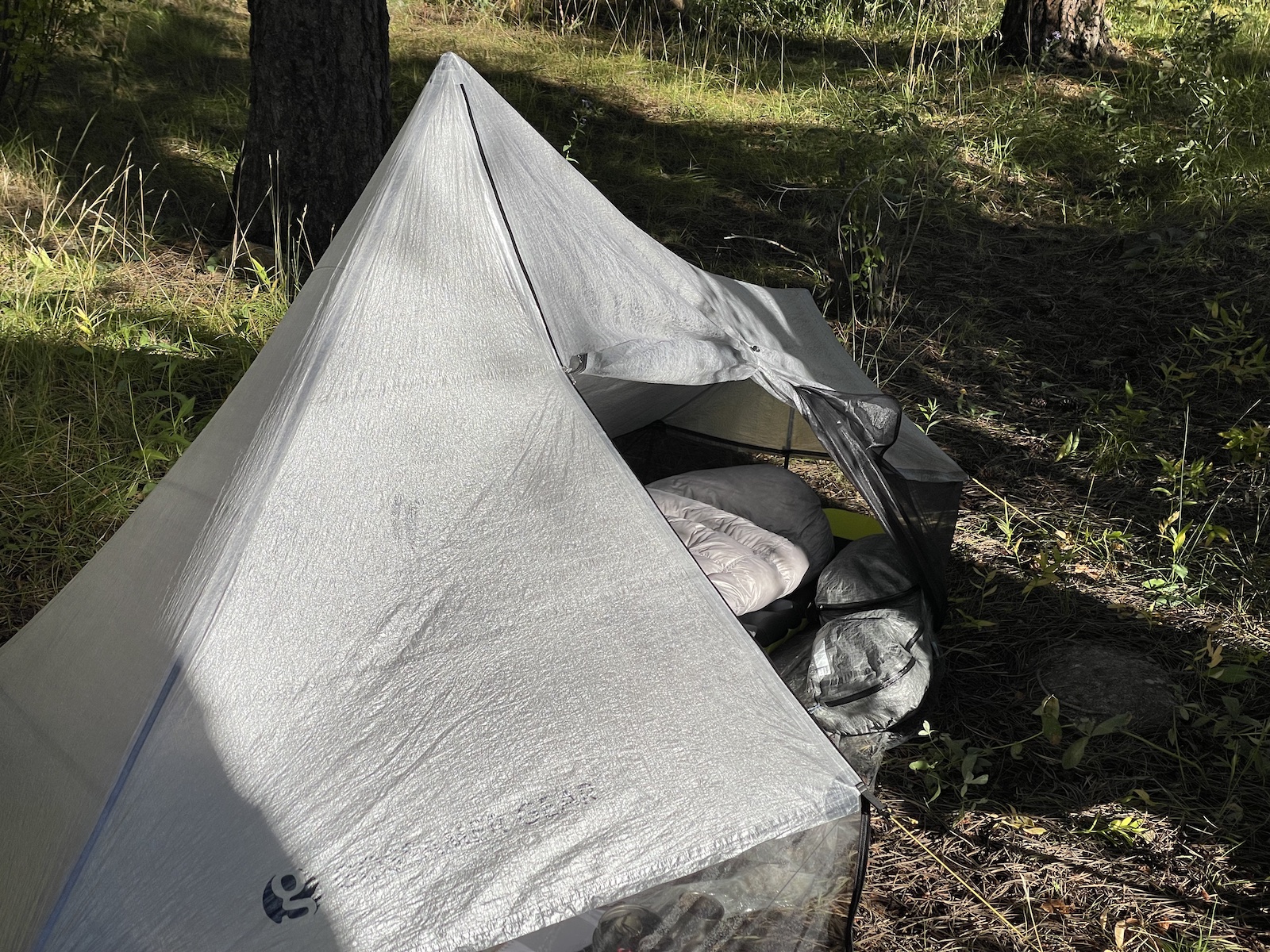 a tent pitched up in the woods next to a tree