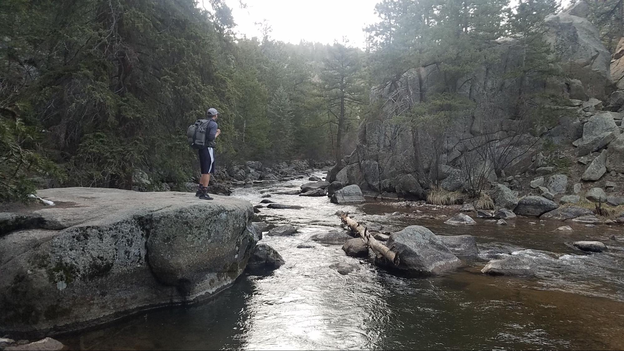 a man standing on a rock next to a river