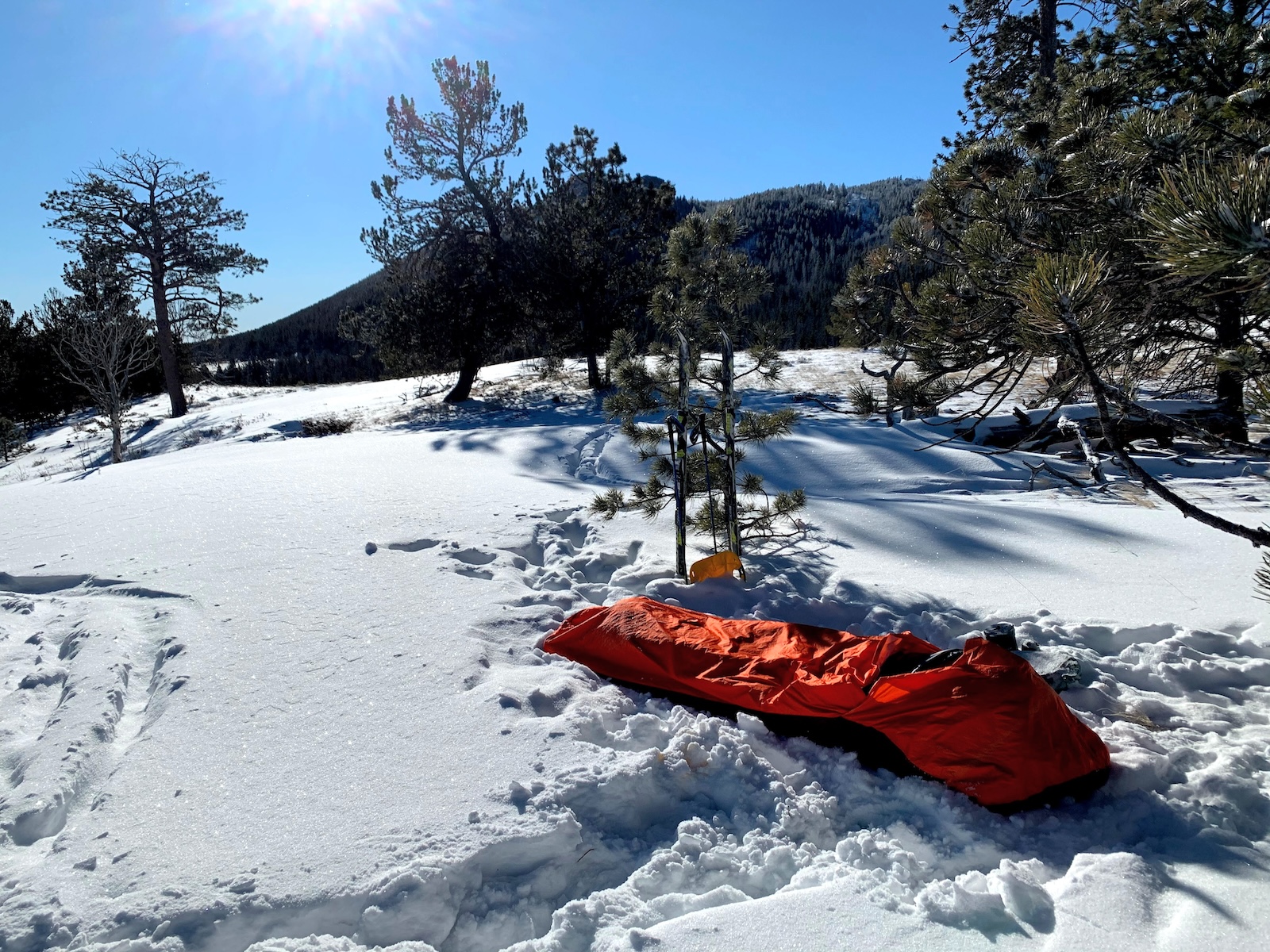 a red sleeping bag sitting on top of snow covered ground