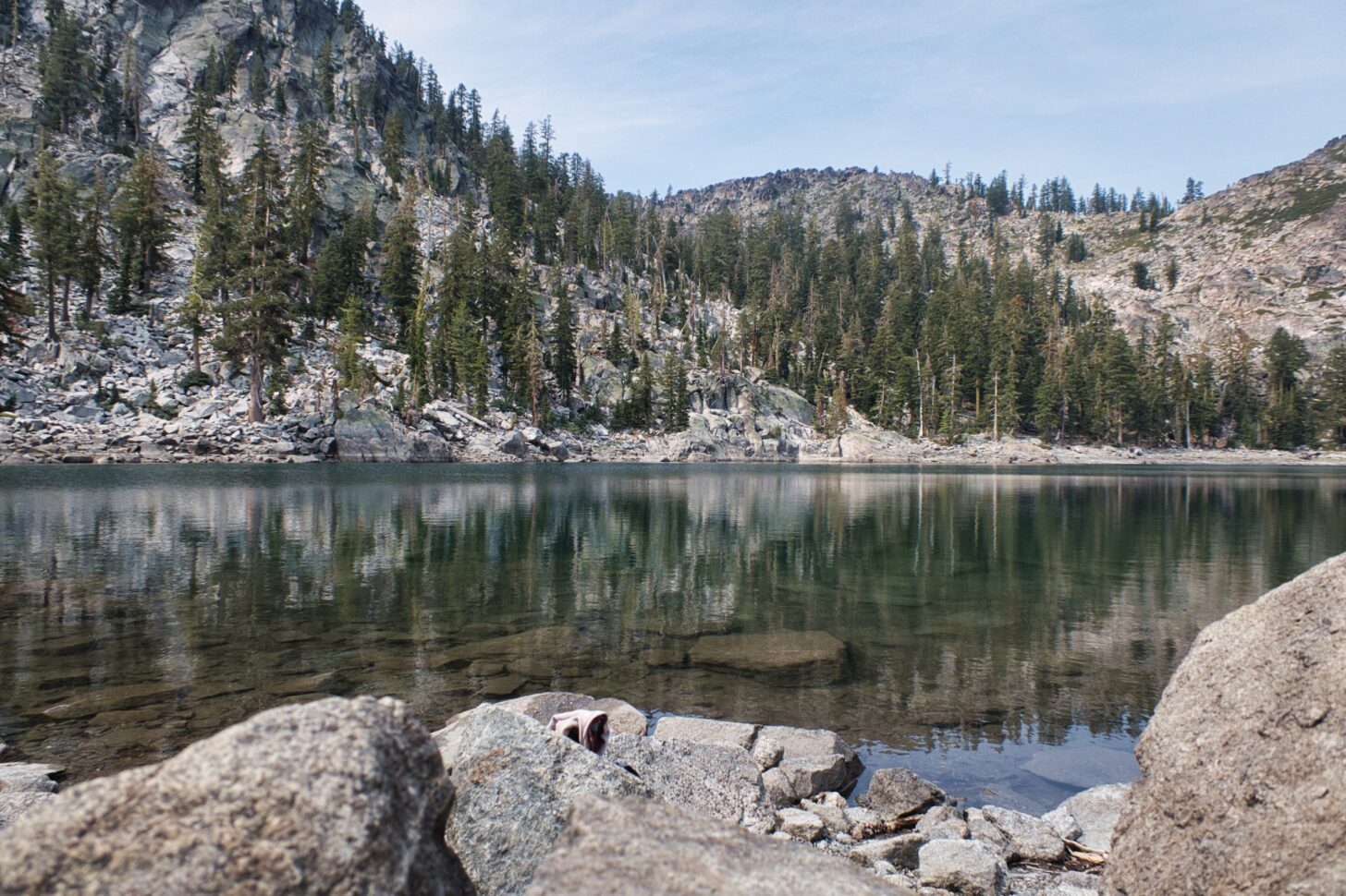 a clear lake with rugged mountains in the background.