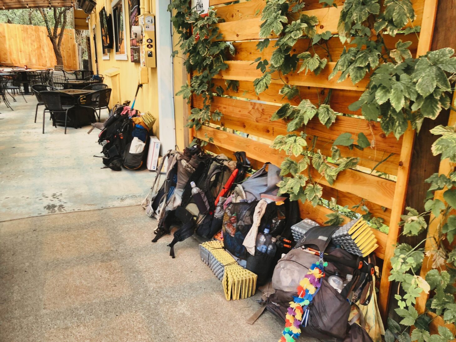 A line of characteristically scruffy backpacks outside the door of a restaurant.