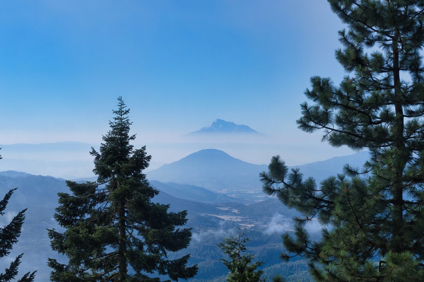 a huge, rugged mountain looms out of the clouds far in the distance.