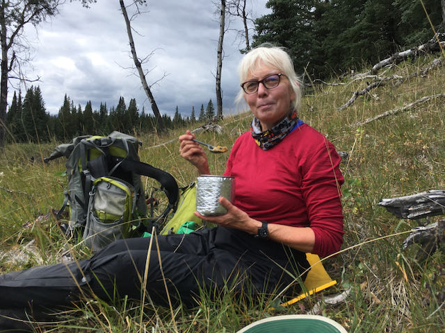 woman eating food on the trail while backpacking