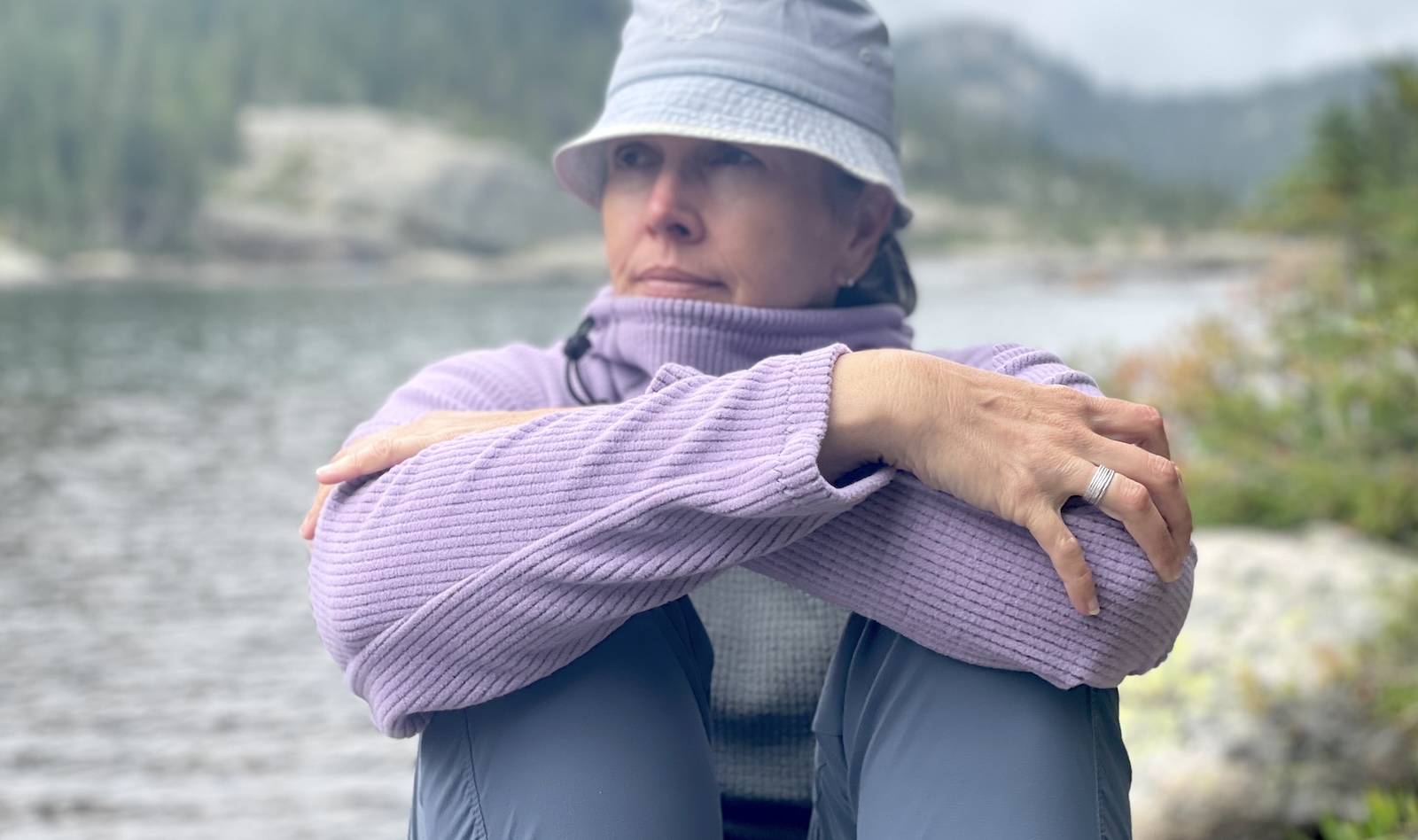 a woman sitting on a rock near a body of water