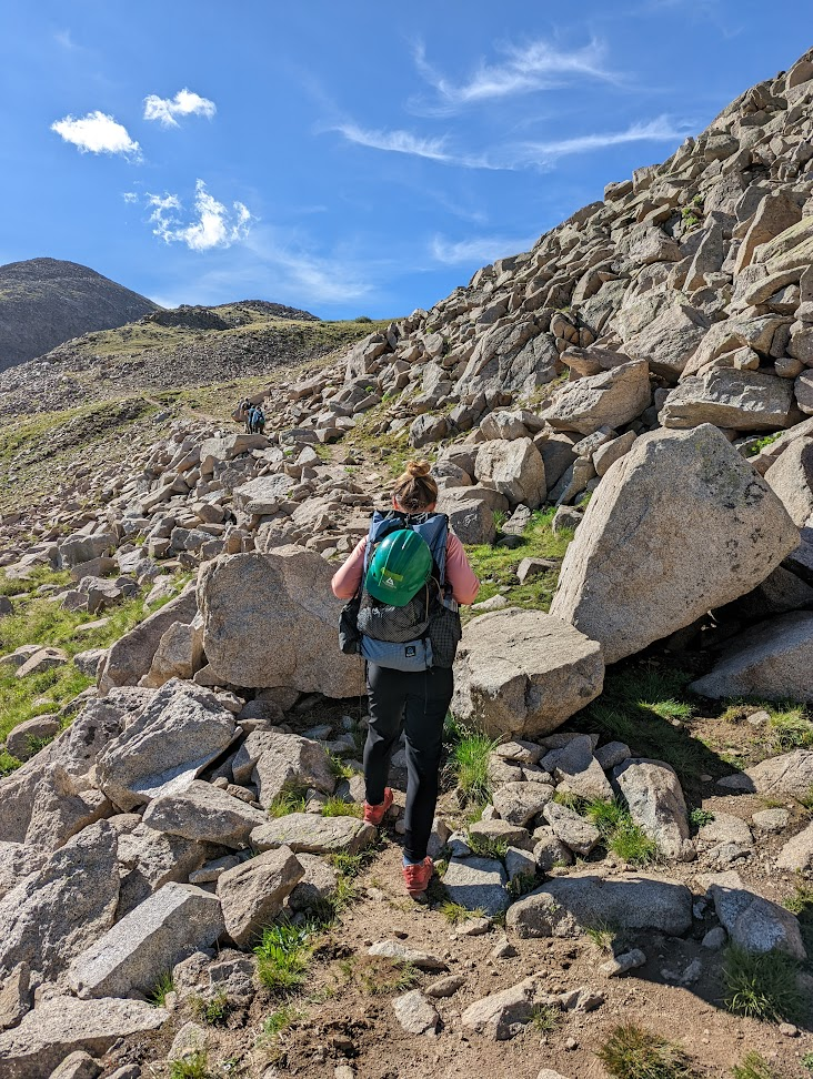 a person with a backpack walking up a rocky hill