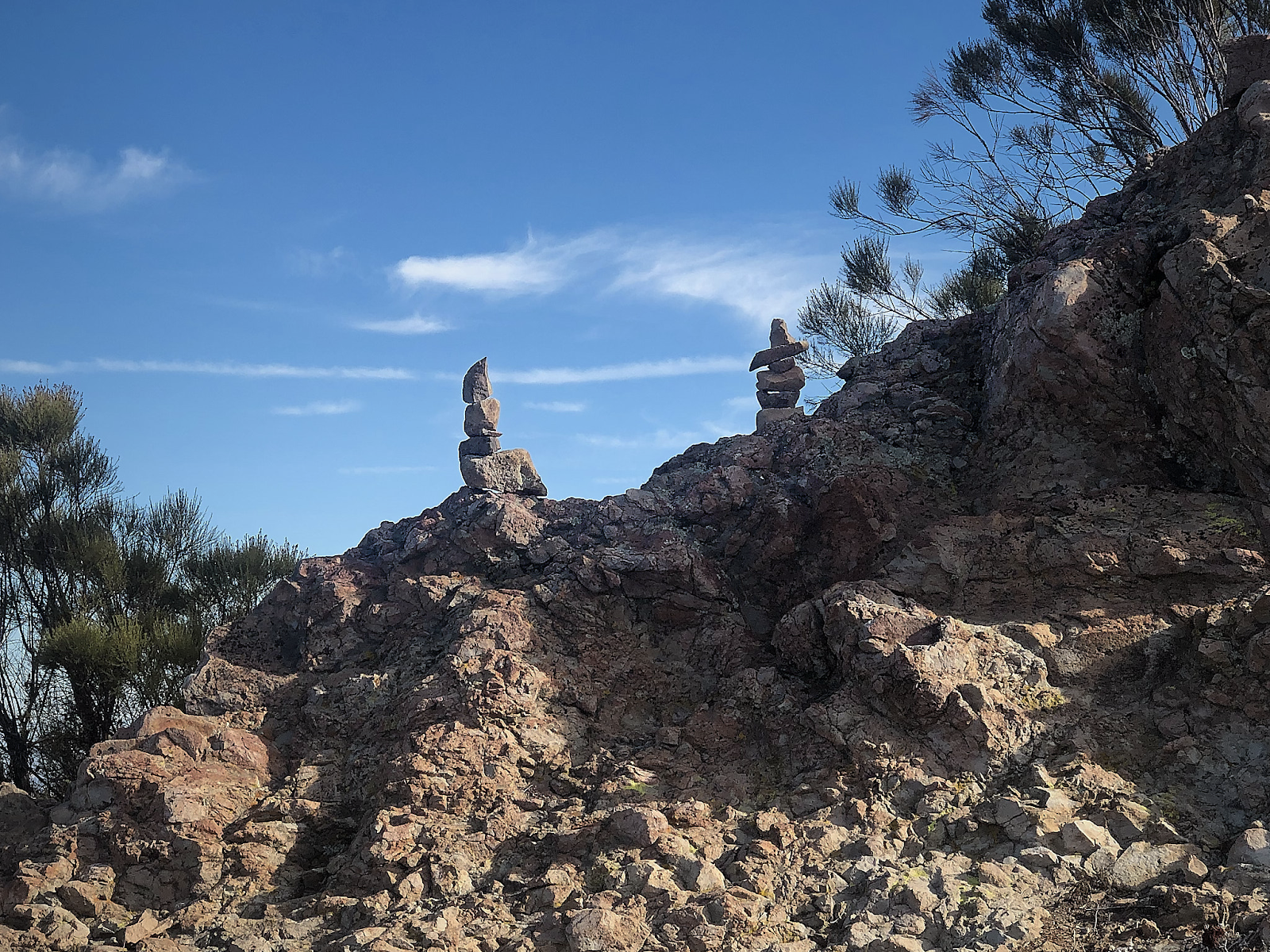 three rocks stacked on top of each other on a rocky hillside